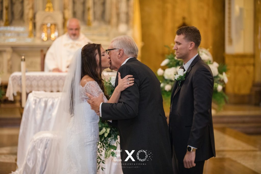 bride kissing her father as he leaves her at the altar