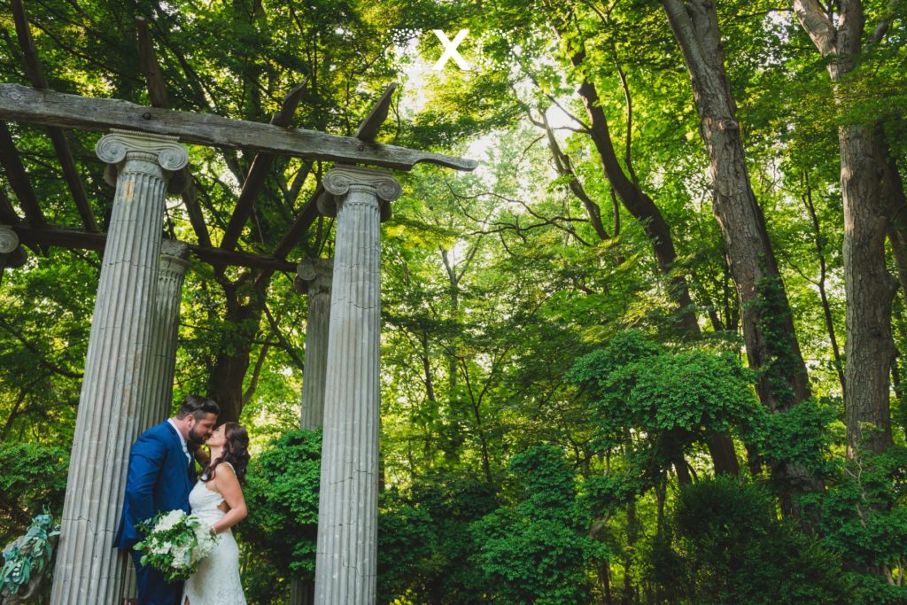 bride and groom kissing by columns