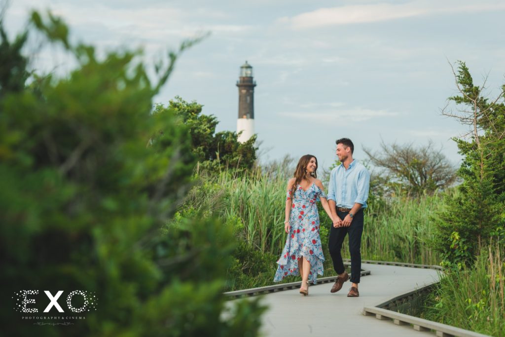 couple walking on boardwalk in front of the Fire Island Lighthouse
