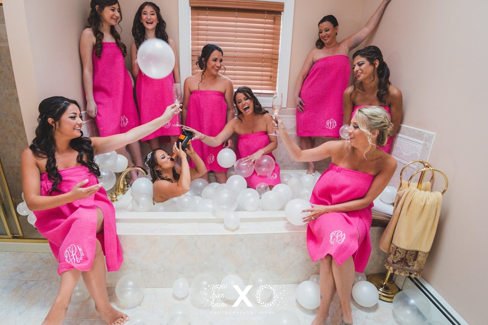 bridesmaids surrounding bride in bath with champagne