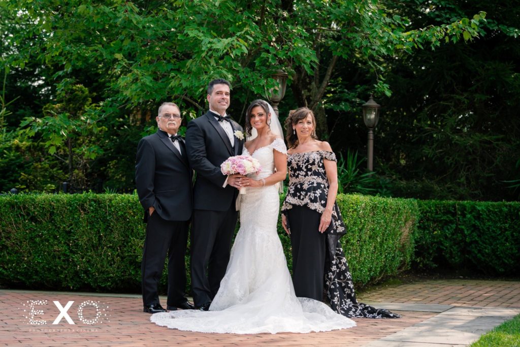 bride and groom with bride's parents outside Crest Hollow Country Club