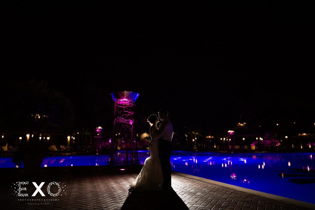 bride and groom kissing by the pool at night