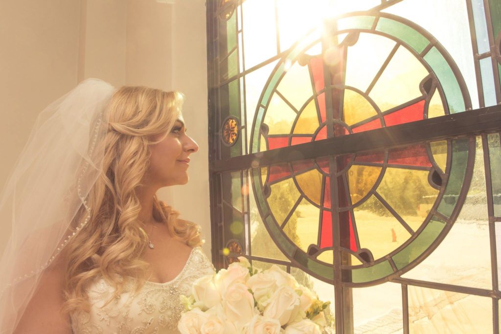 beautiful bride in church window before The Mansion at Oyster Bay reception