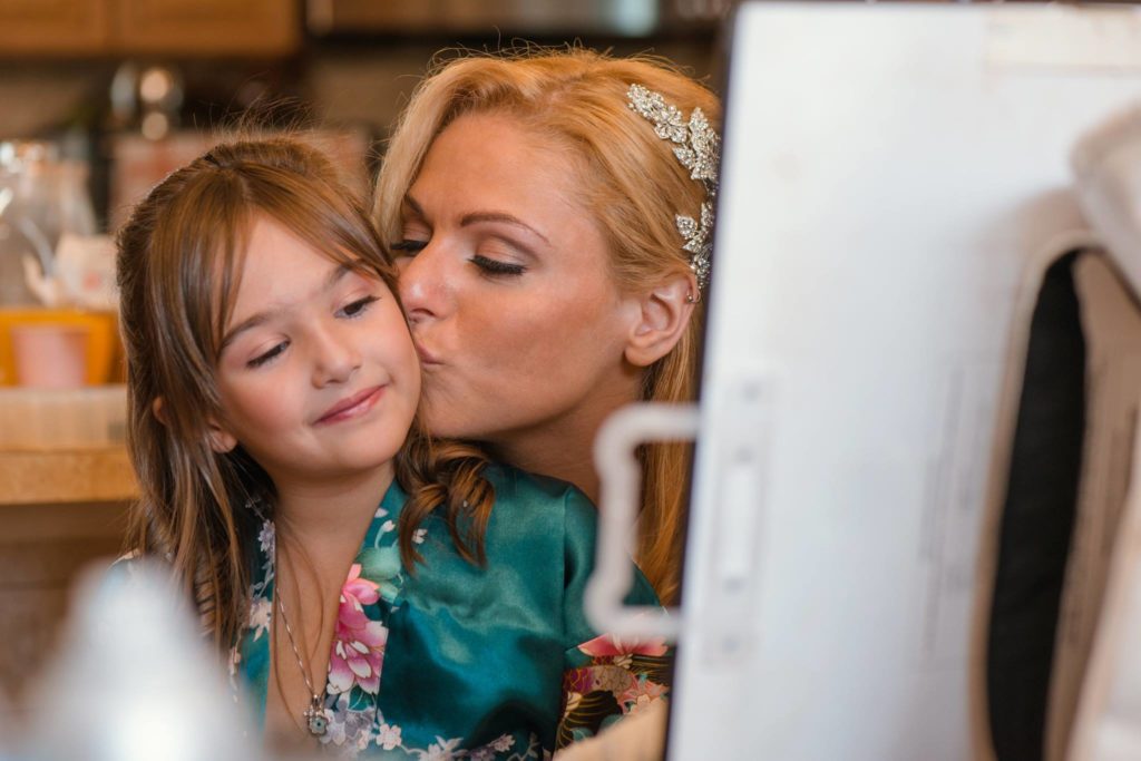 bride kissing flower girl while getting ready for the The Mansion at Oyster Bay wedding