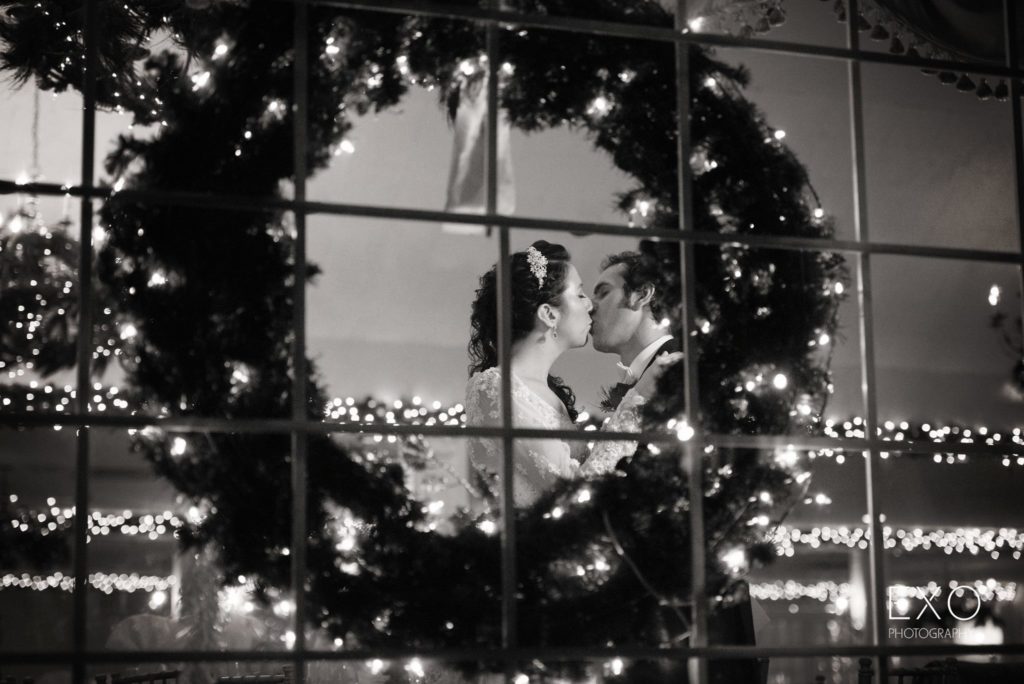 bride and groom kissing behind a wreath at The Milleridge Cottage