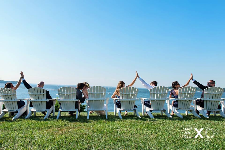 bridal party sitting in chairs on the beach