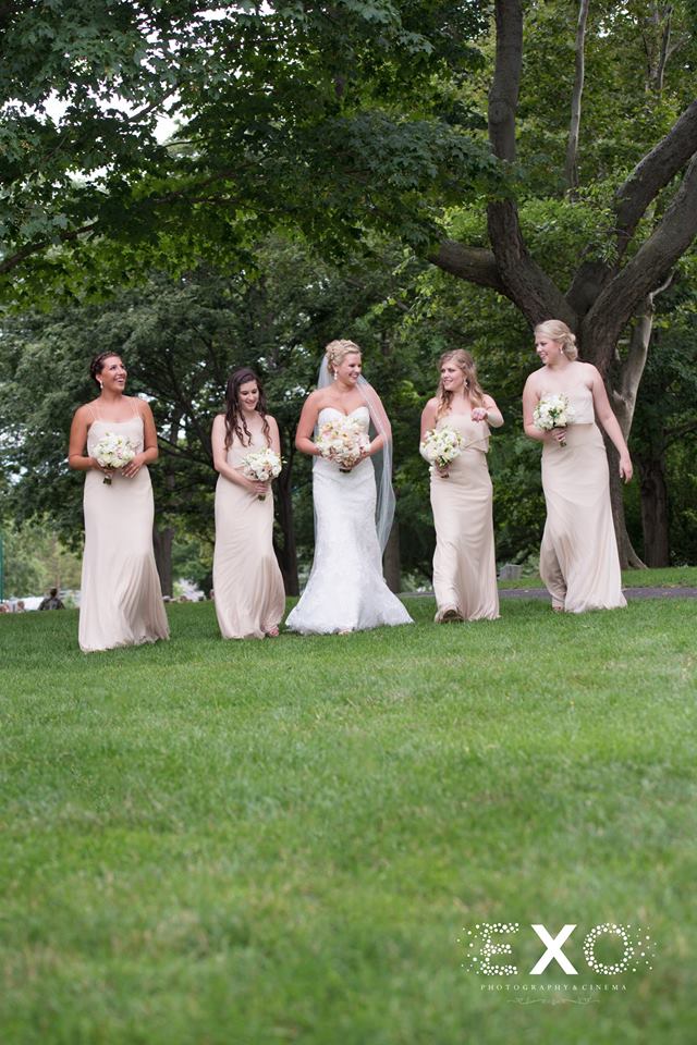 bride and her bridesmaids walking in field outside The Thayer Hotel
