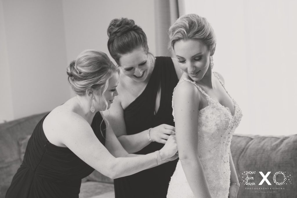 bride getting help with her dress from bridesmaids