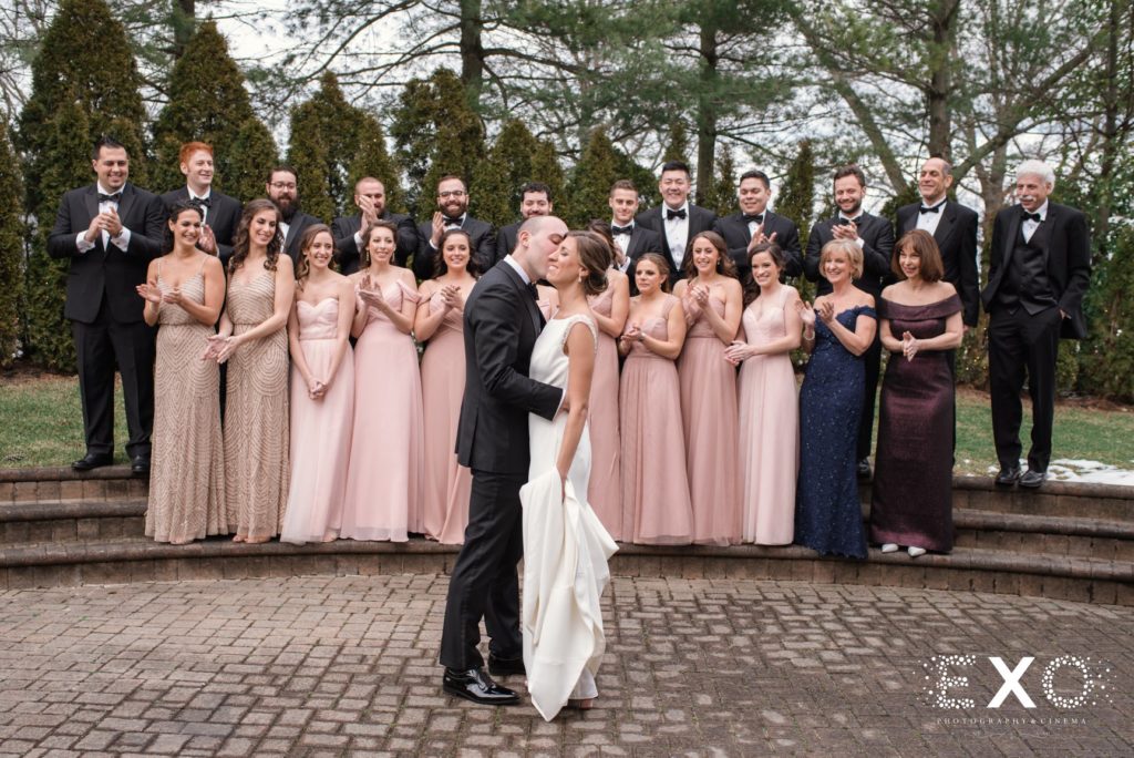 bride and groom kissing in front of bridal party