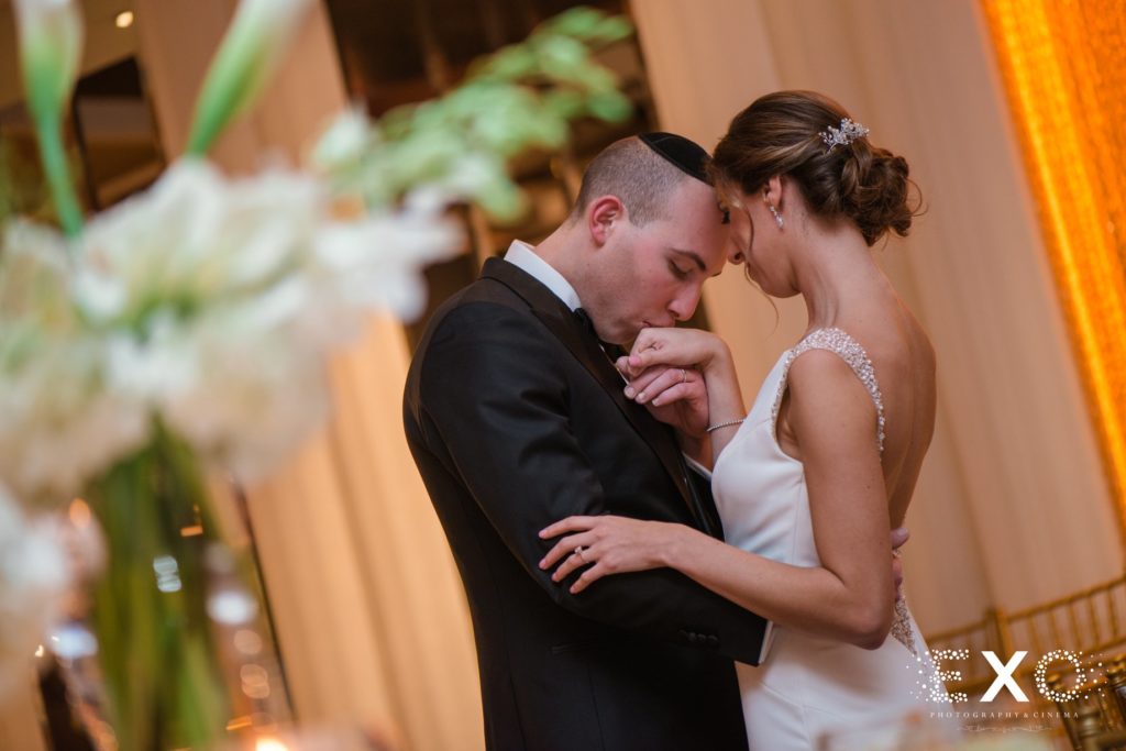 groom kissing bride's hand at Temple Beth Torah