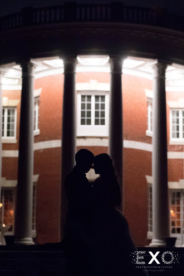 bride and groom in front of Bourne Mansion at night