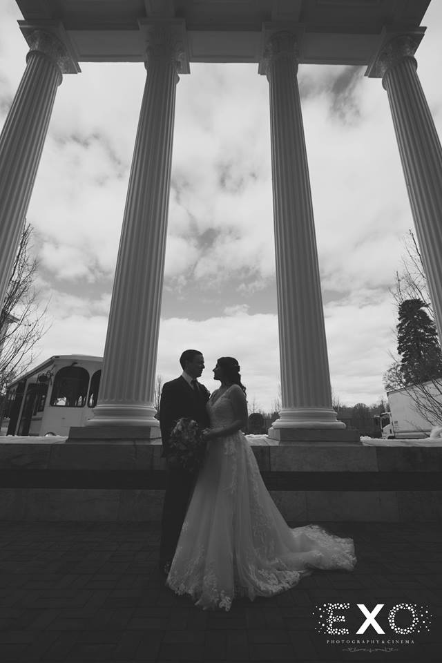 bride and groom under columns at Bourne Mansion