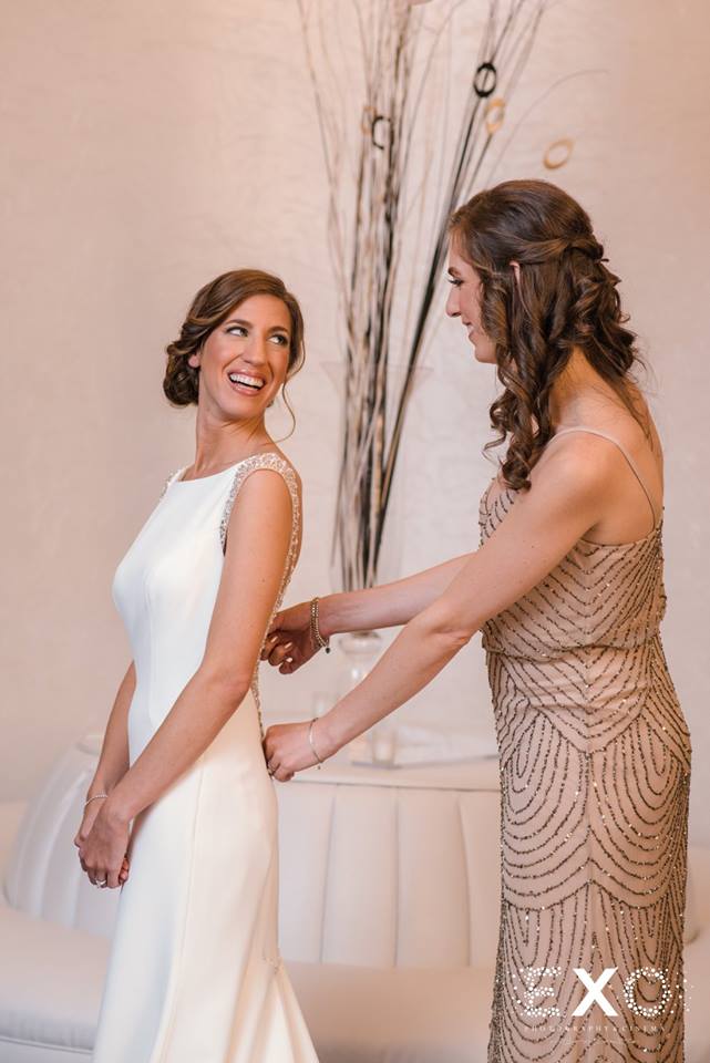 bride's sister helping her zip her dress