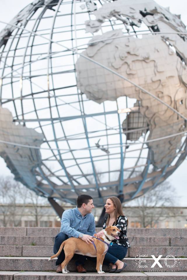 couple sitting by the globe petting their dog