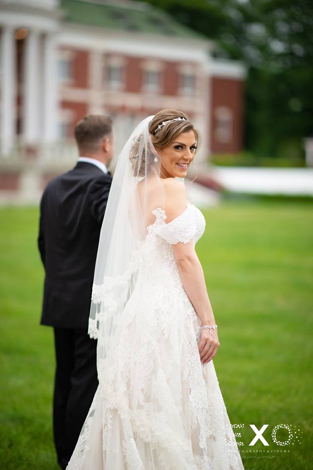 bride looking at camera while walking through lawn at Bourne Mansion