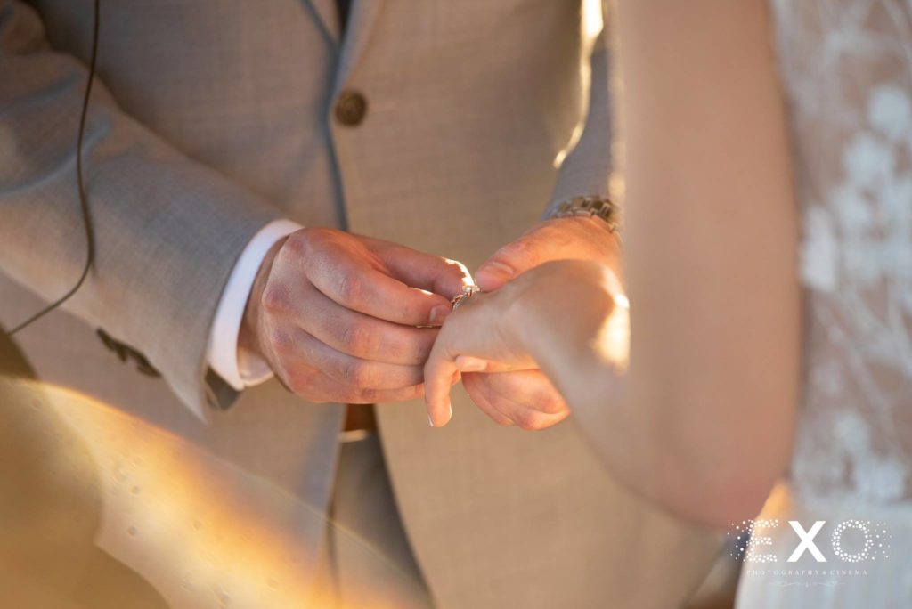 groom putting ring on bride's finger at Atlantis Aquarium