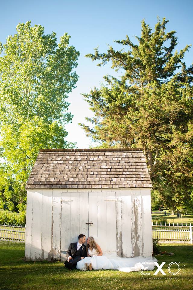 bride and groom sitting outside against shed