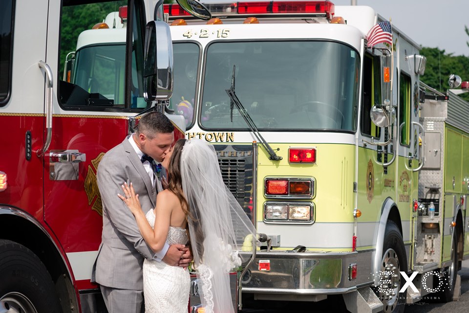 bride and groom kissing by fire trucks