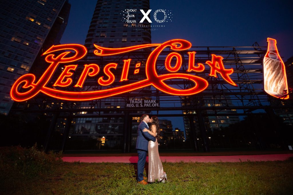 couple kissing in front of Pepsi sign at Gantry Plaza State Park