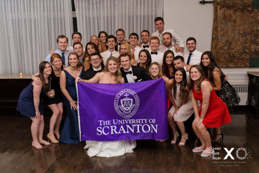 bride and groom with guests holding a university of scranton flag at The Carltun