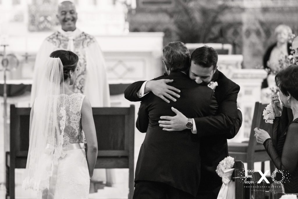 groom hugging bride's father at the end of the aisle