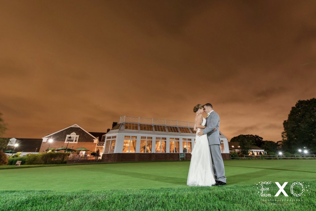 bride and groom on the lawn outside Carlyle on the Green at night