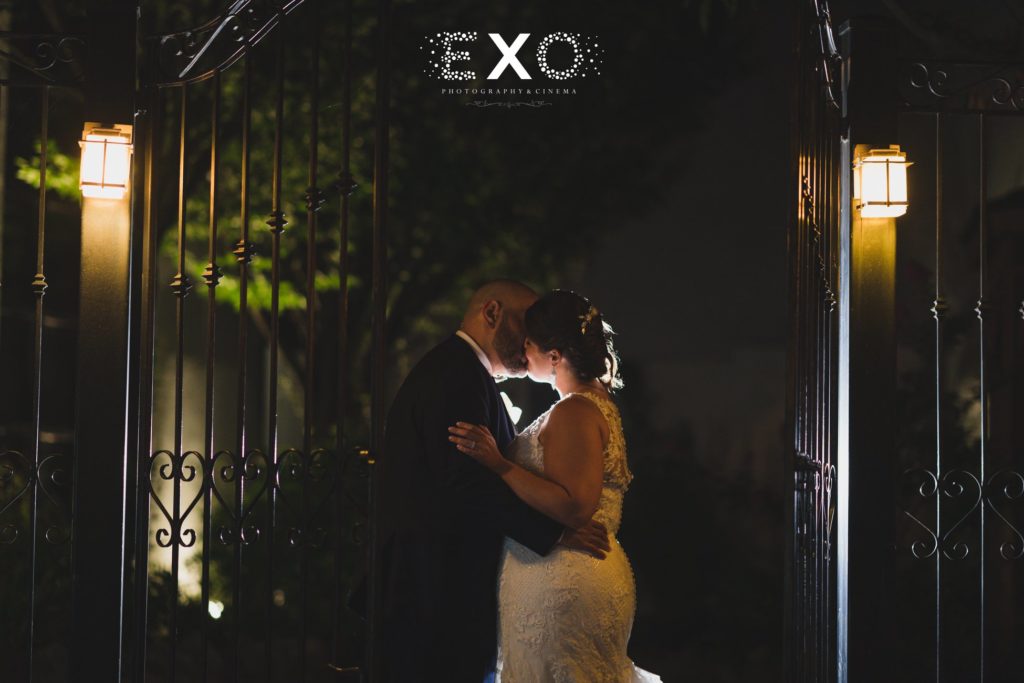 bride and groom kissing by the gate outside The Loft by Bridgeview