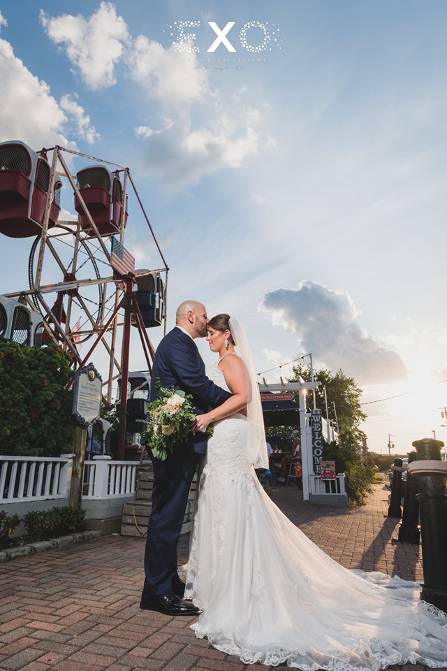 groom kissing bride in front of ferris wheel