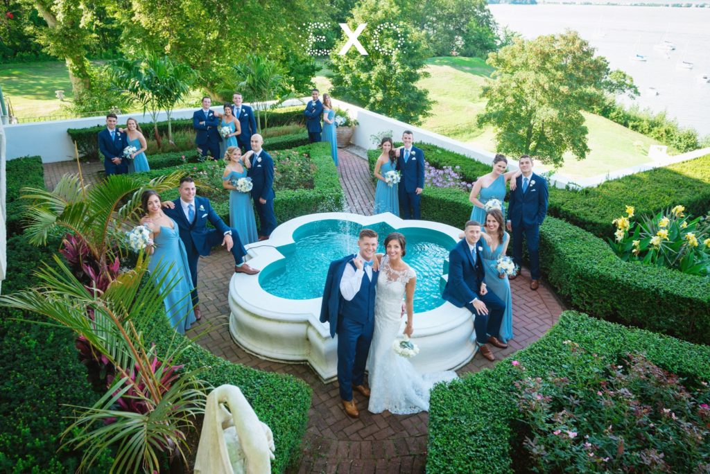 bride and groom with their bridal party by the fountain outside Harbor Club at Prime