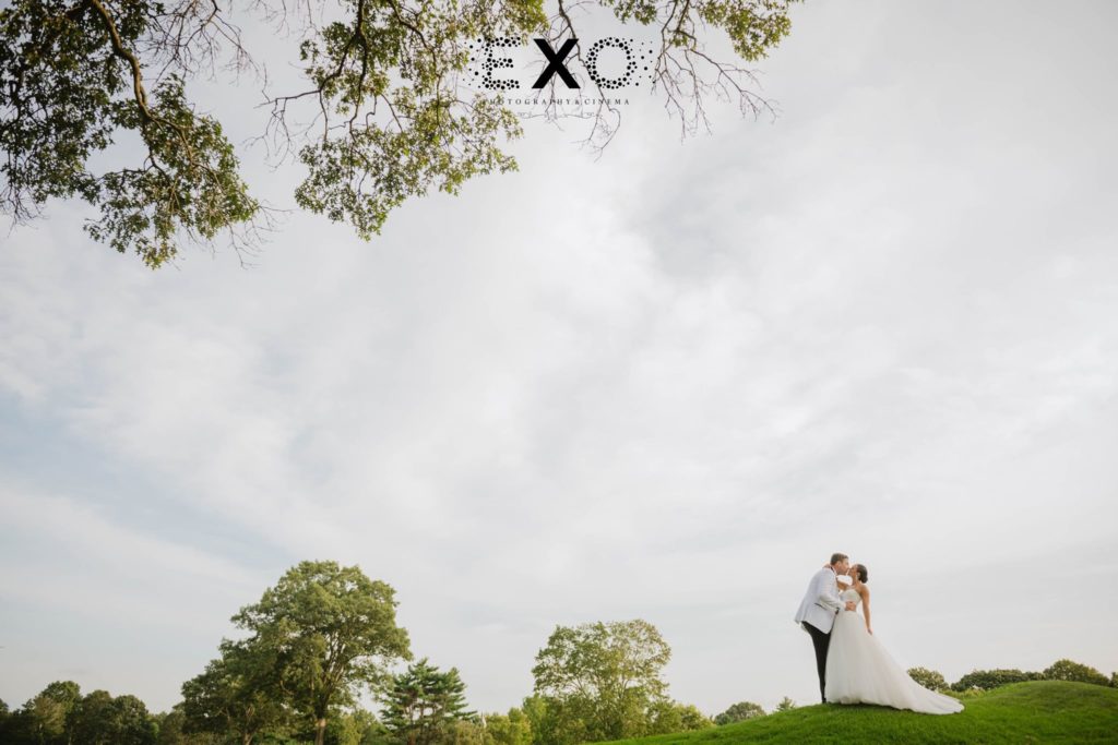 bride and groom kissing on the golf course at Muttontown Country Club
