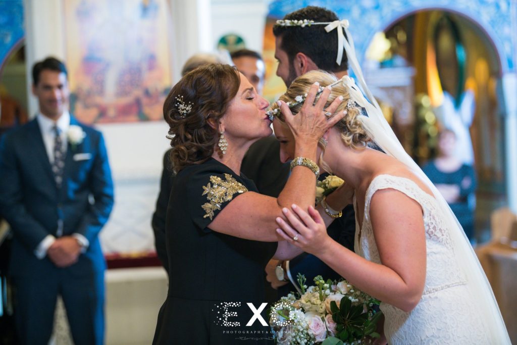 mother kissing bride's head during ceremony