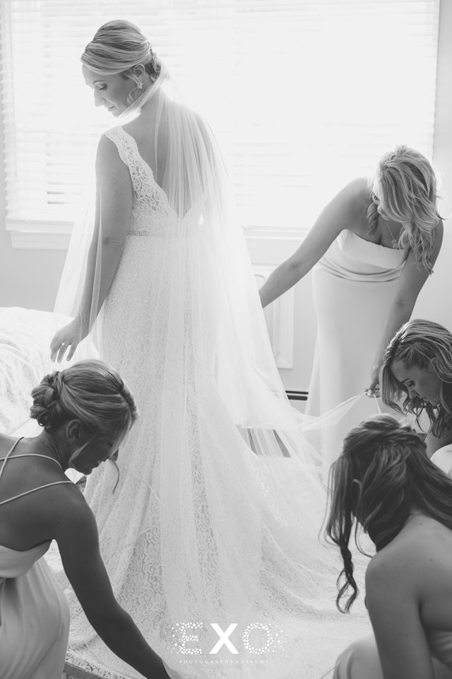 bridesmaids helping the bride with her gown