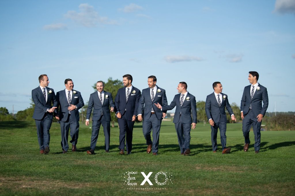 groom and groomsmen walking outside Mansion at Timber Point