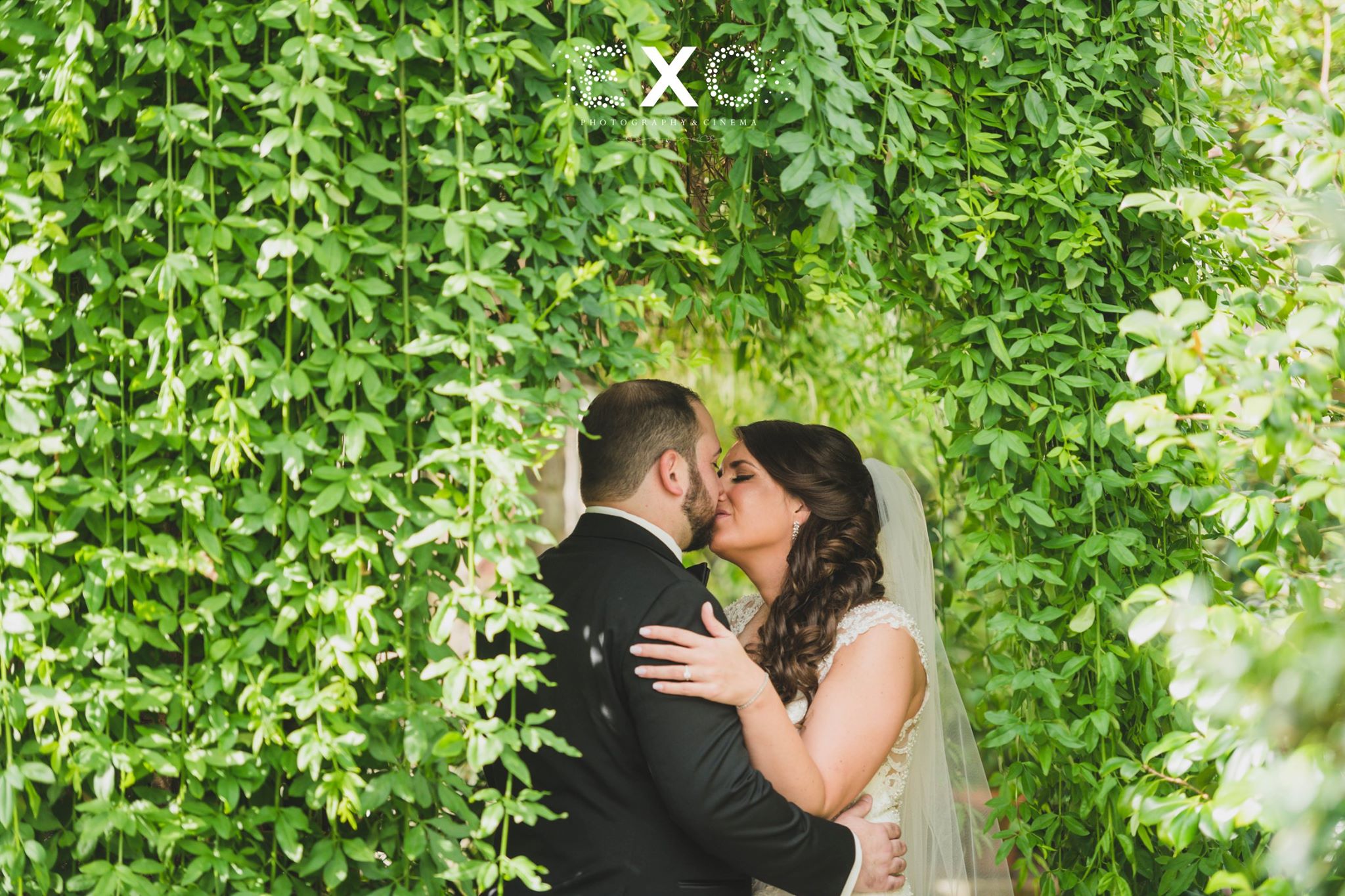 bride and groom kissing in the greenery