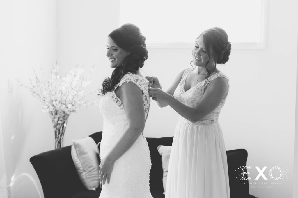 bride getting help with her dress from a bridesmaid