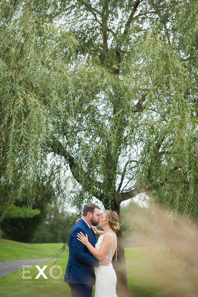 bride and groom kissing under the tree at Willow Creek Golf and Country Club