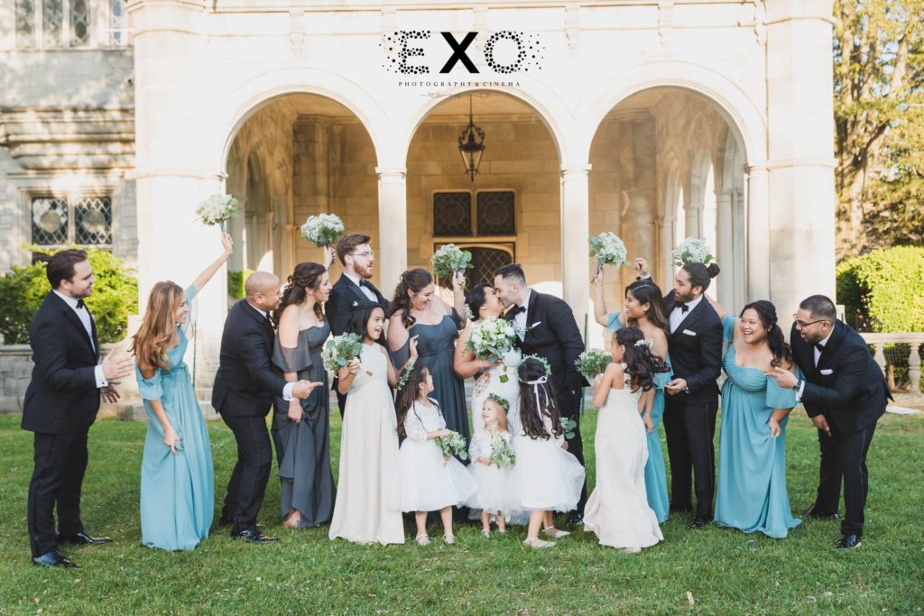 bride and groom kissing with bridal party at Fox Hollow