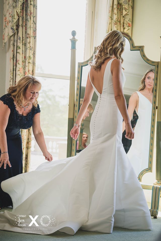 bride looking in the mirror as her mother helps with her gown
