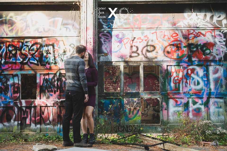 couple kissing in front of graffiti wall