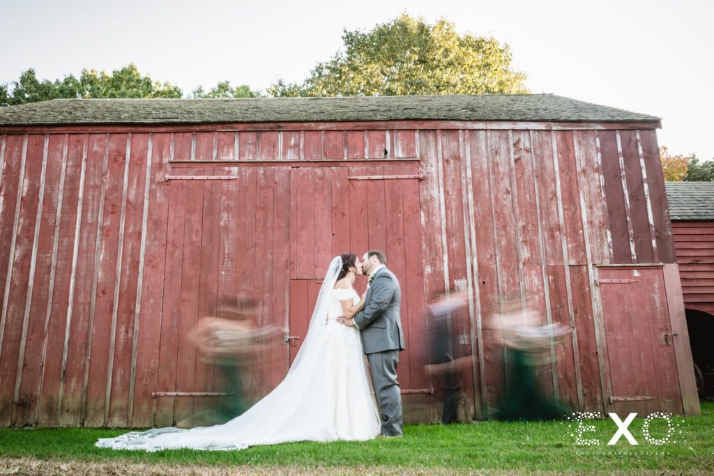 bride and groom kissing outside the barn at Old Bethpage Village Restoration
