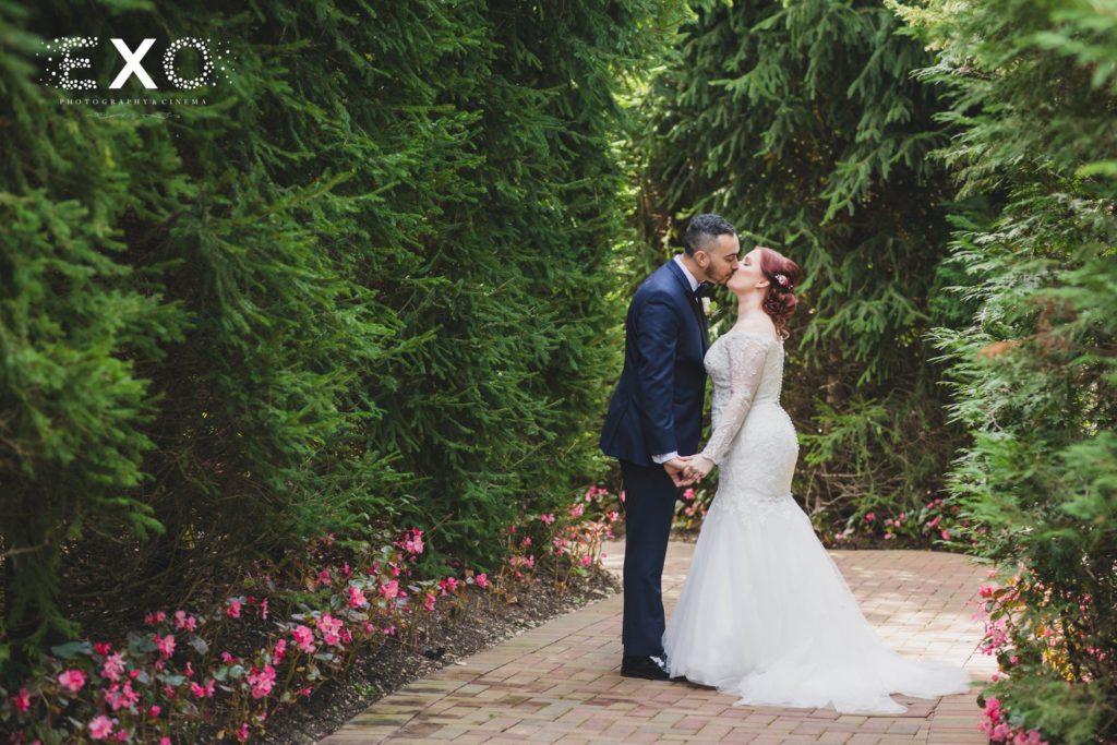 bride and groom kissing in the garden of Crest Hollow Country Club
