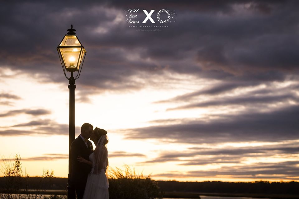 bride and groom kissing by the lamppost at sunset