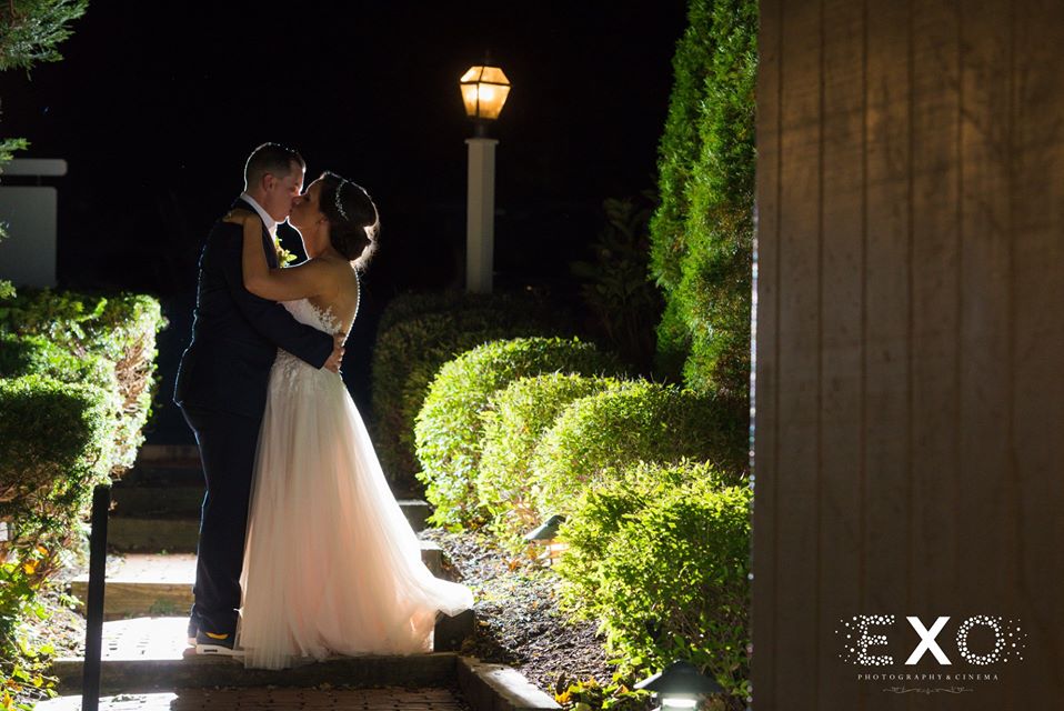 bride and groom kissing outside Three Village Inn at night