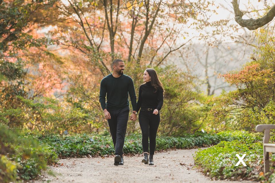 couple holding hands and walking through Planting Fields Arboretum