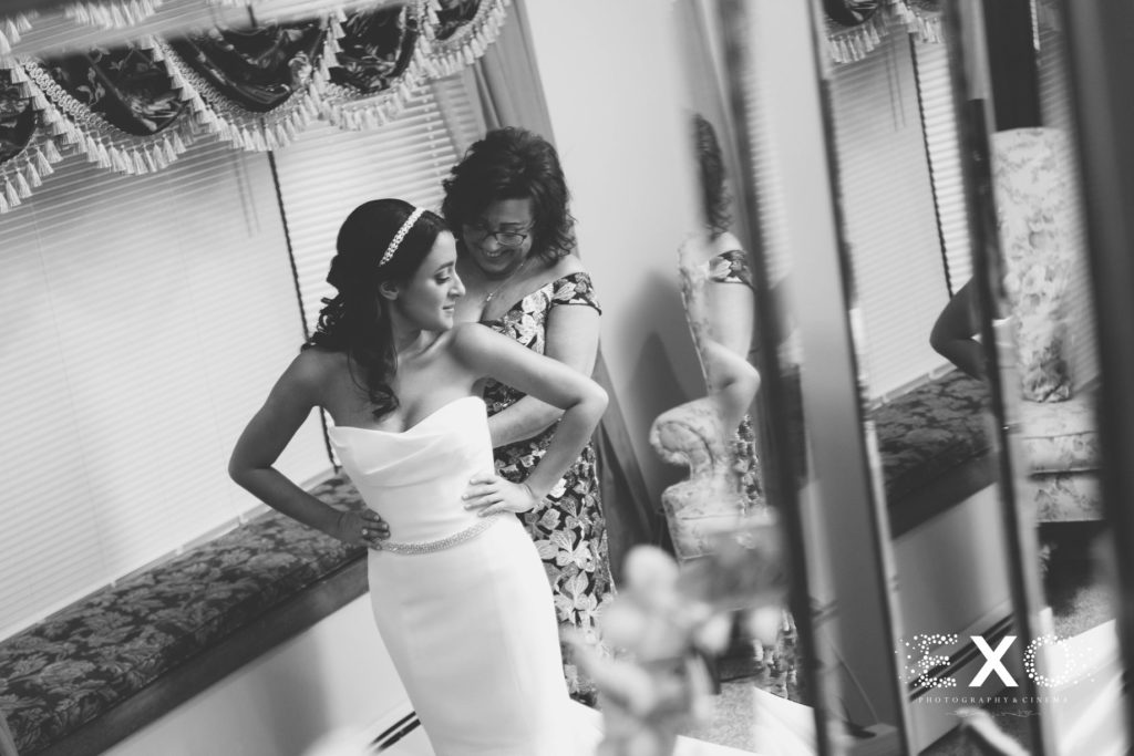 bride getting help with her dress from her mother