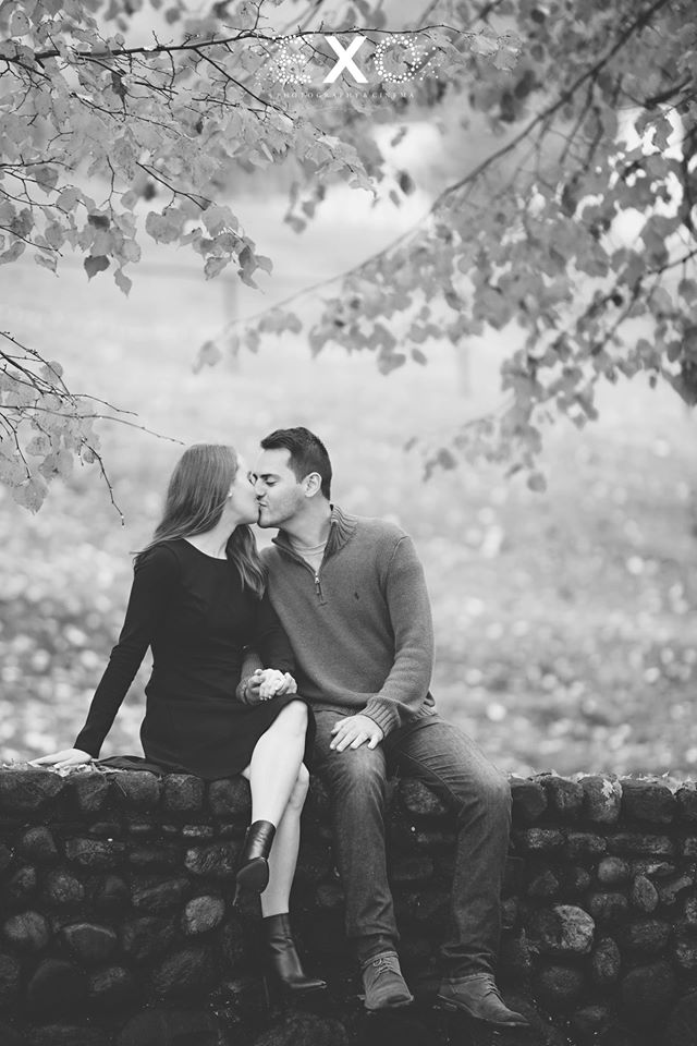 couple kissing while sitting on the stone wall