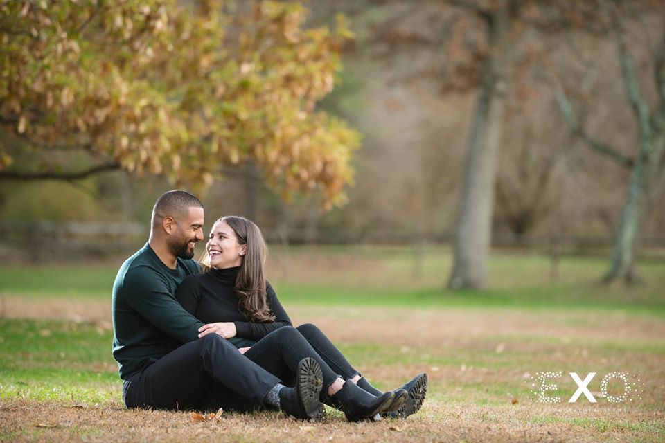 couple laughing while sitting in the grass at Planting Fields Arboretum