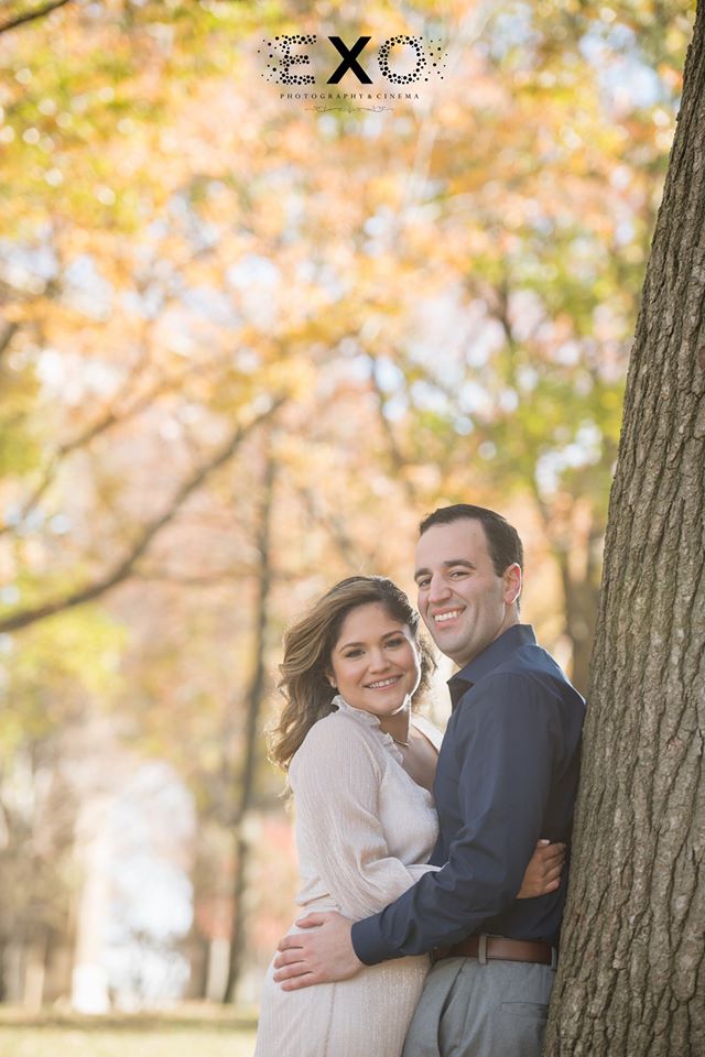 couple smiling leaning against a tree