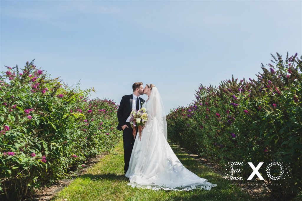 bride and groom kissing among the flowers at Salt Air Farm