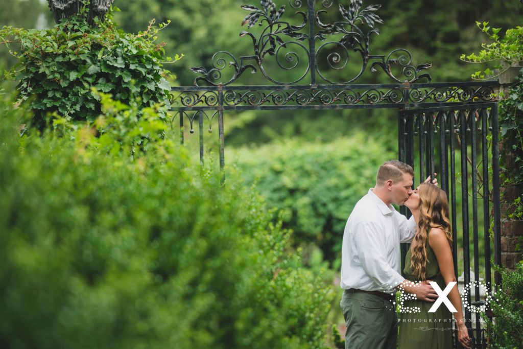 couple kissing at the gate at Planting Fields Arboretum